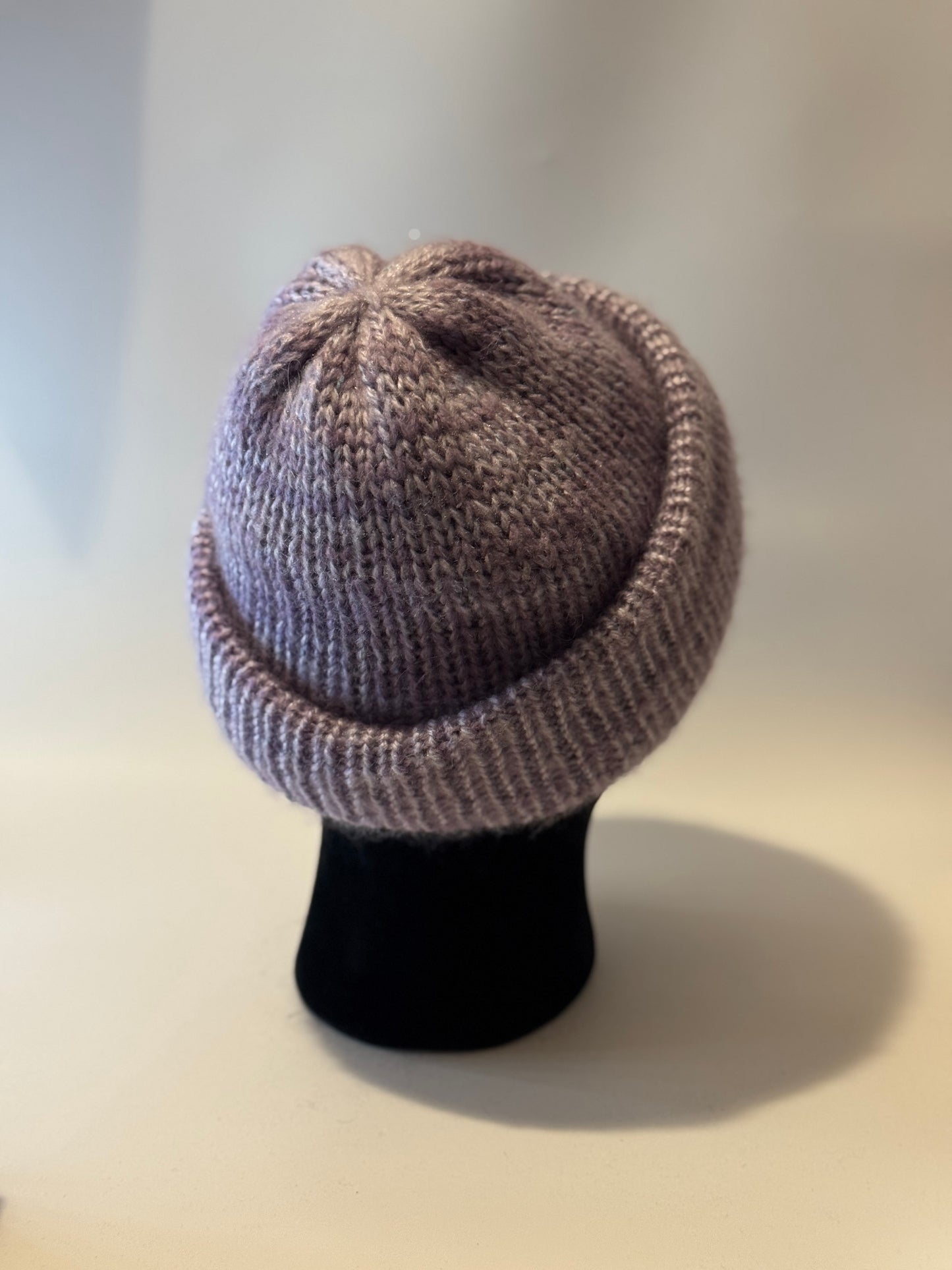 Knitted beanie on a mannequin head against a plain background