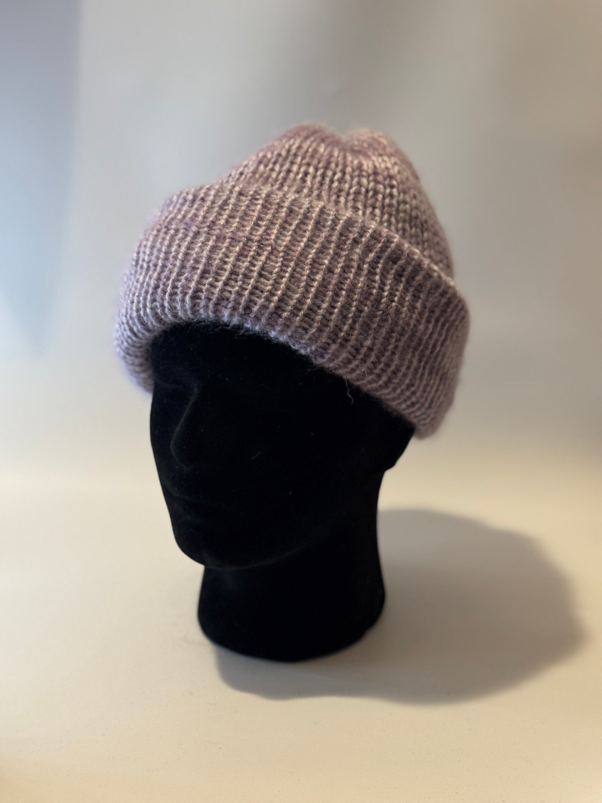 Knitted beanie on a black mannequin head against a plain background